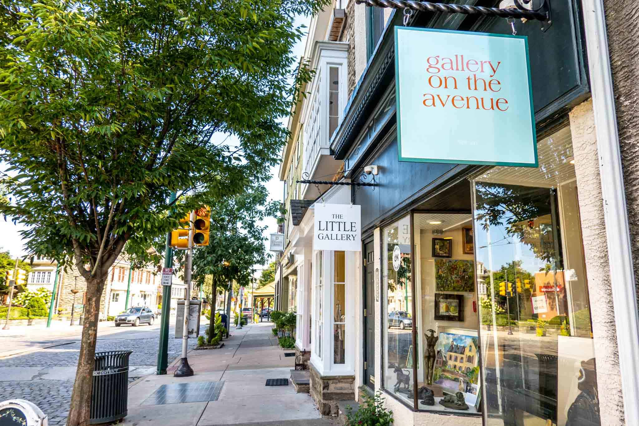 Sunlit shopfronts and a leafy cobblestone street along Germantown Avenue in Chestnut Hill, Philadelphia